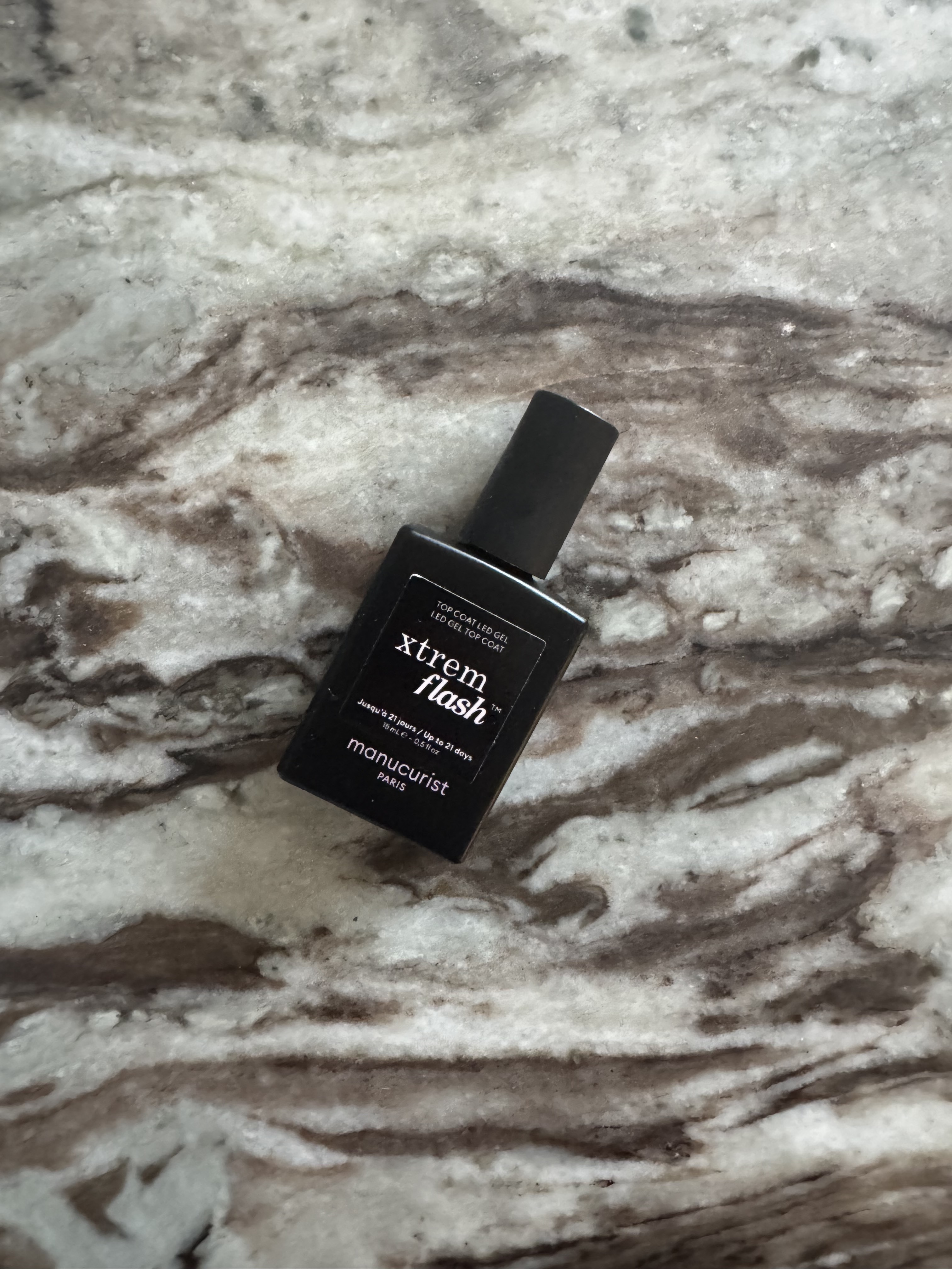 The Manucurist Xtrem Flash Top Coat on a marble table