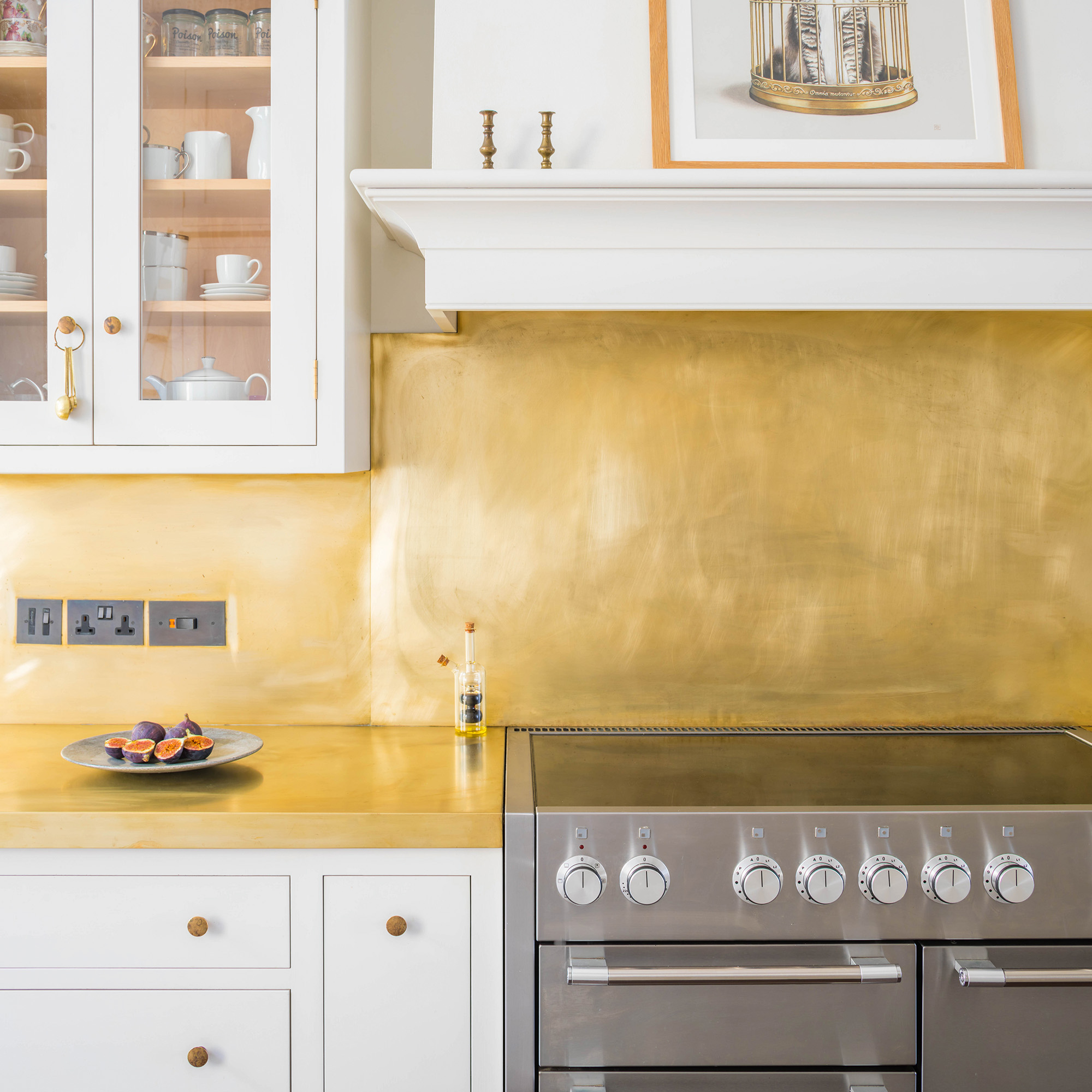 brass splashback in white kitchen above grey oven