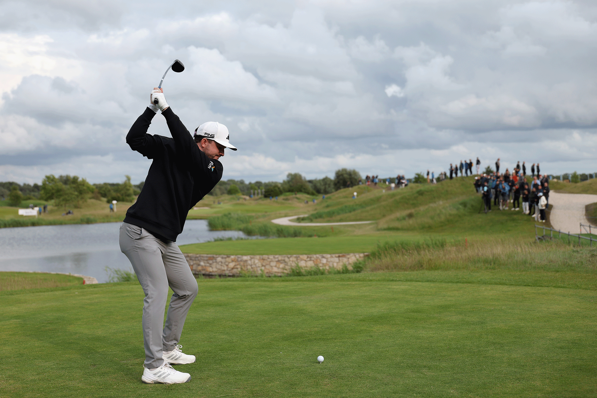 Richie Ramsay at the top of his backswing with driver, about to hit the ball down a narrow fairway with water all the way down the left