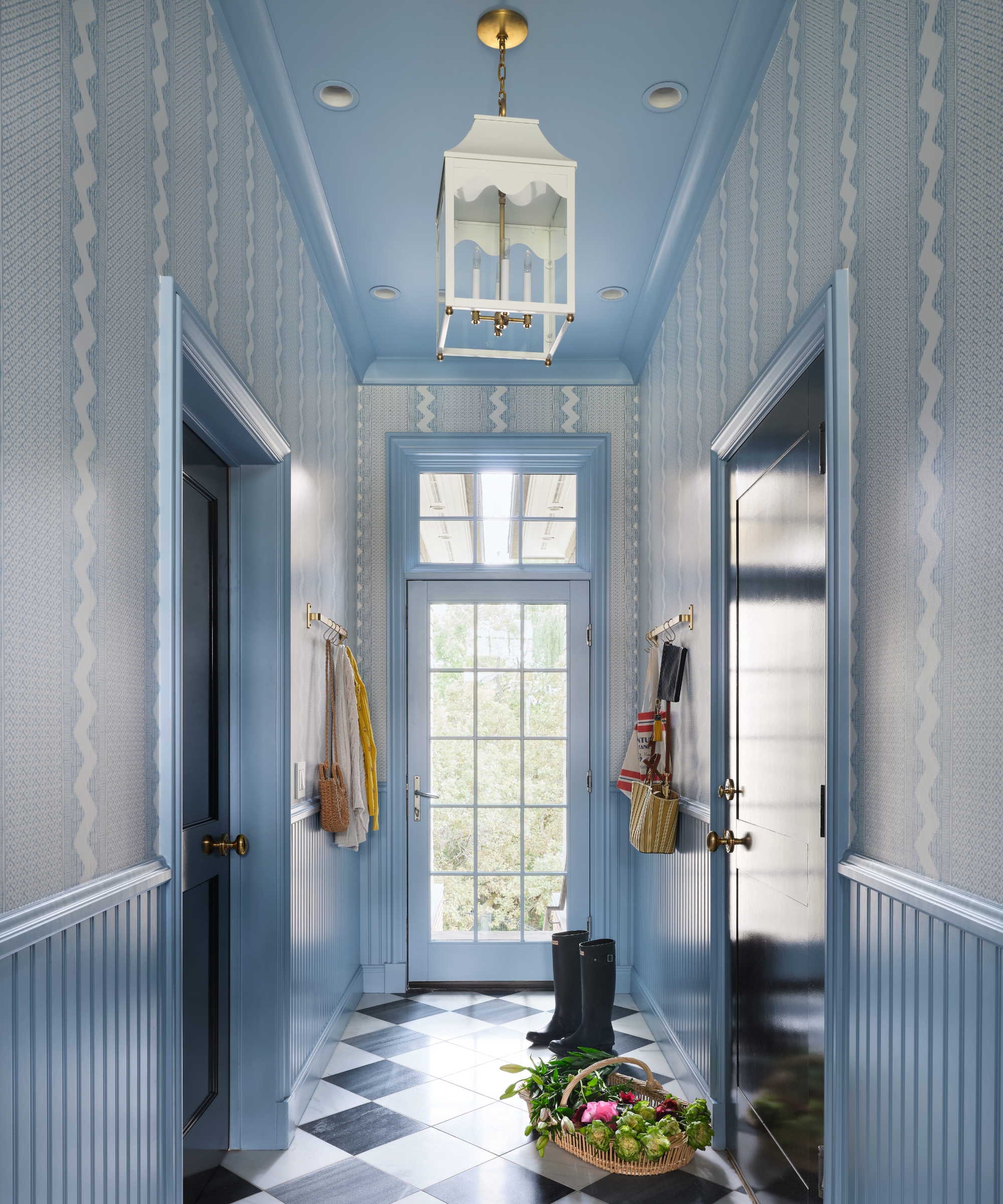 Blue mudroom with patterned wallpaper, beadboard wainscoting, dark blue doors, a checkerboard floor and a glazed garden door.