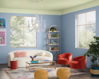 living room with light blue walls and light green ceiling, white curved sofa and two red armchairs