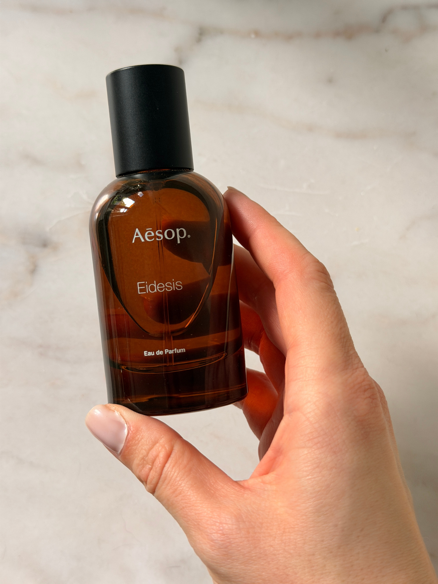 Grace holding a bottle of Aesop perfume