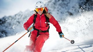 A woman in a red oneskie skiing in the Alps