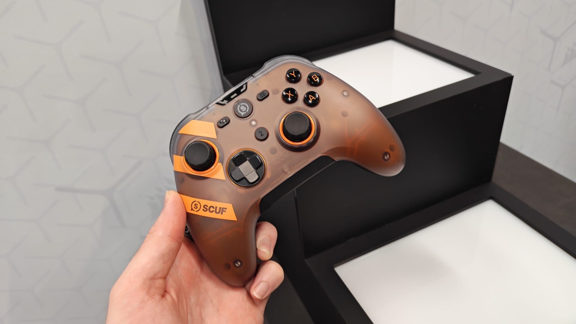 Hand holding Scuf Nemesis Pro 8K controller in front of black and white backdrop