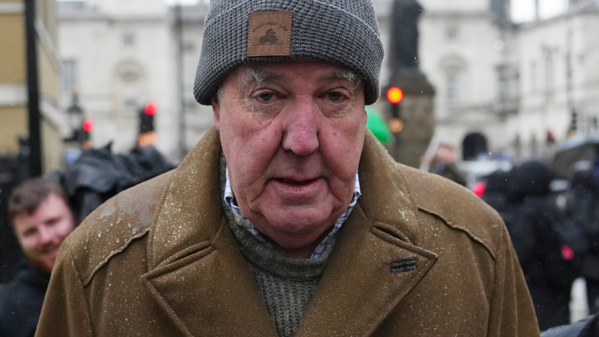 TV presenter Jeremy Clarkson at a farmers rally on 19 November 2024, wearing a grey woolly hat and a brown coat, which is wet