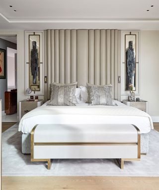 Bedroom wall light ideas showing a bed with a grand beige headboard, grey striped cushions and large decorative wall lights