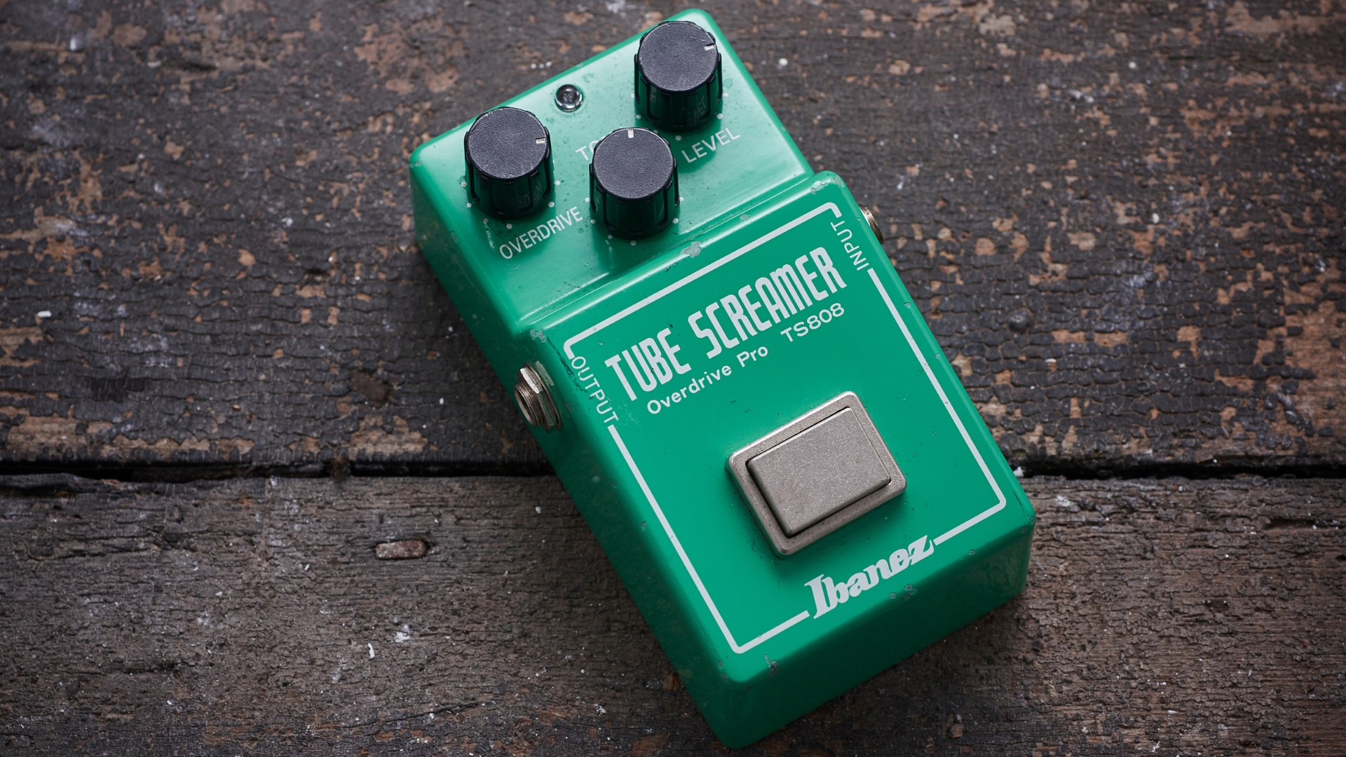 An Ibanez Tube Screamer TS808 overdrive pedal on a worn wooden floor