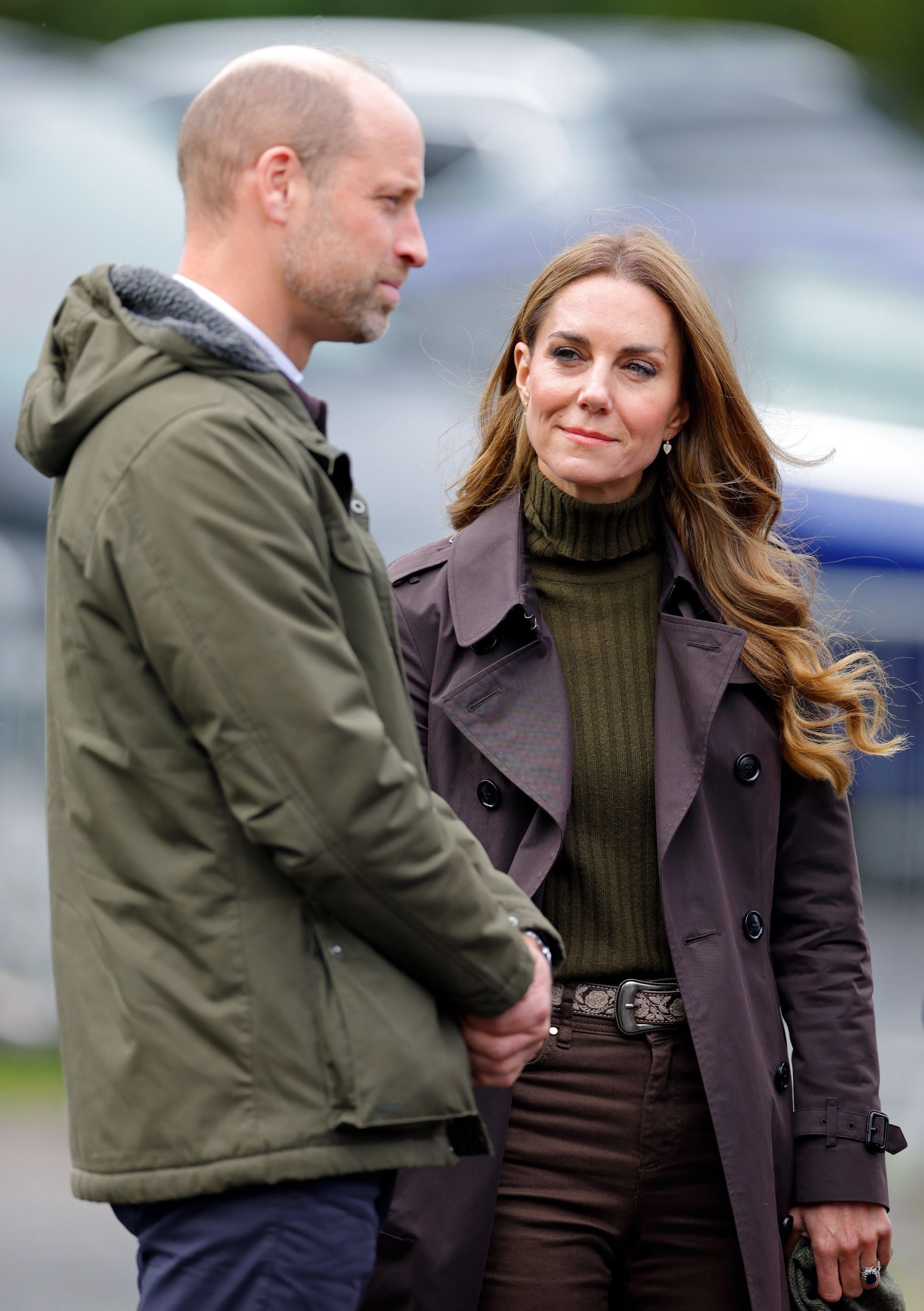 Princess Kate wearing a coat and sweater smiling at Prince William