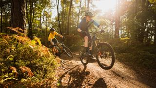 Two mountain bikers riding a dusty trail at golden hour
