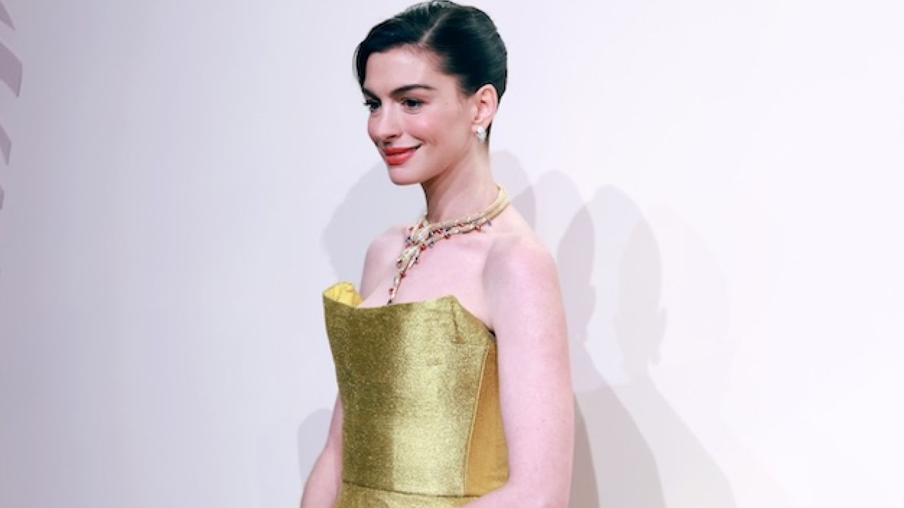 Anne Hathaway wearing a gold strapless midi dress with bulgari jewelry