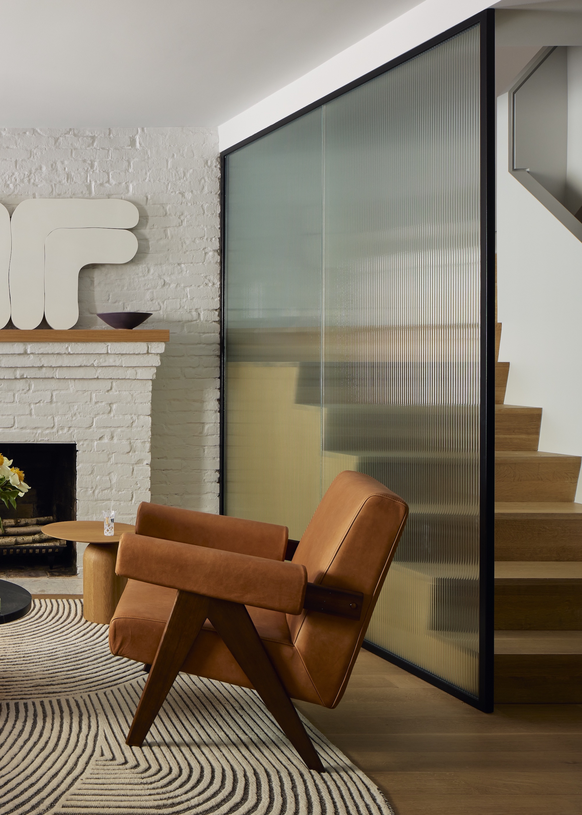 staircase with fluted glass screen and orange armchair