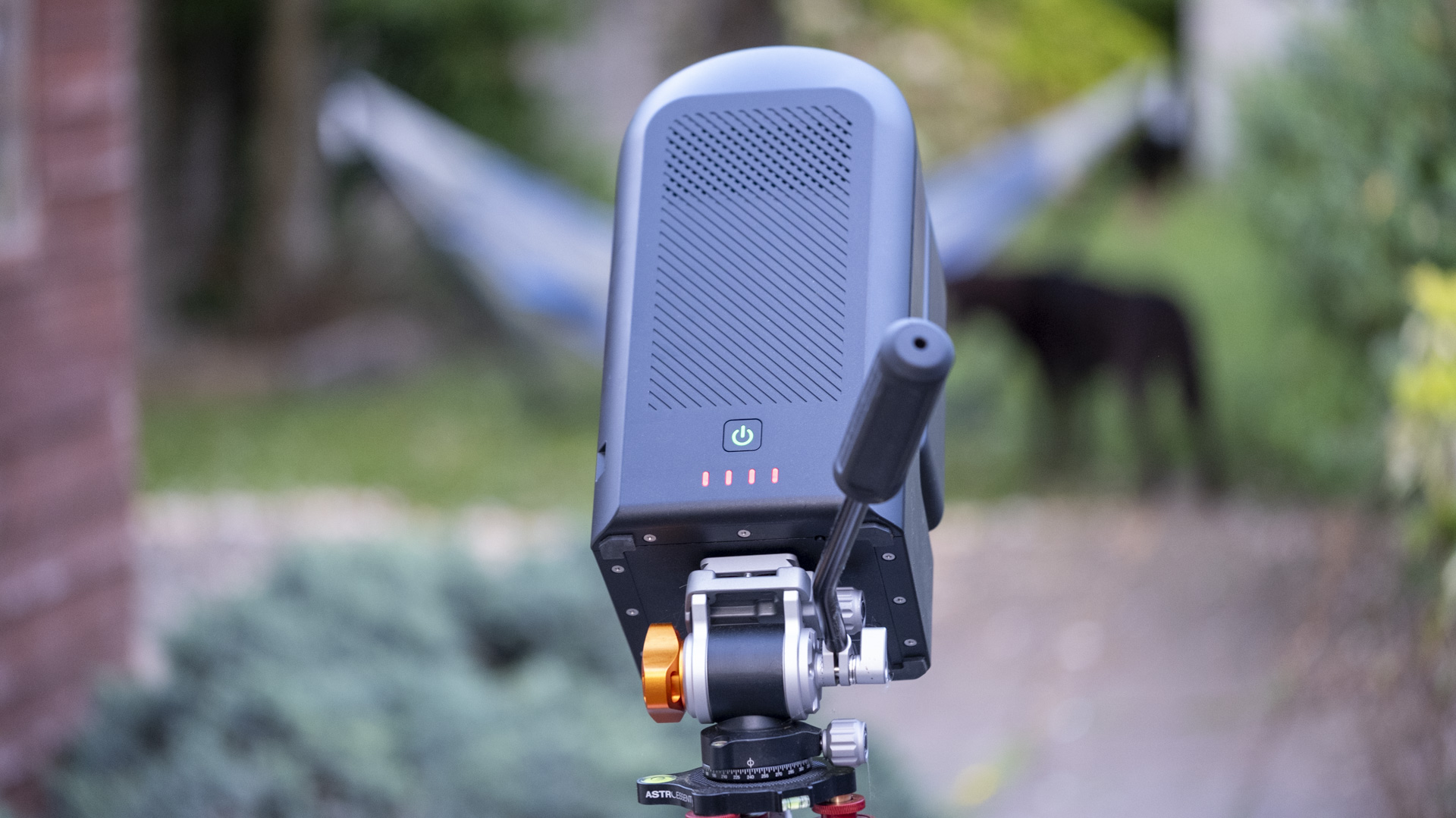 The ZWO Seestar S50 smart telescope in a garden in the daylight. In the background are trees and a dog