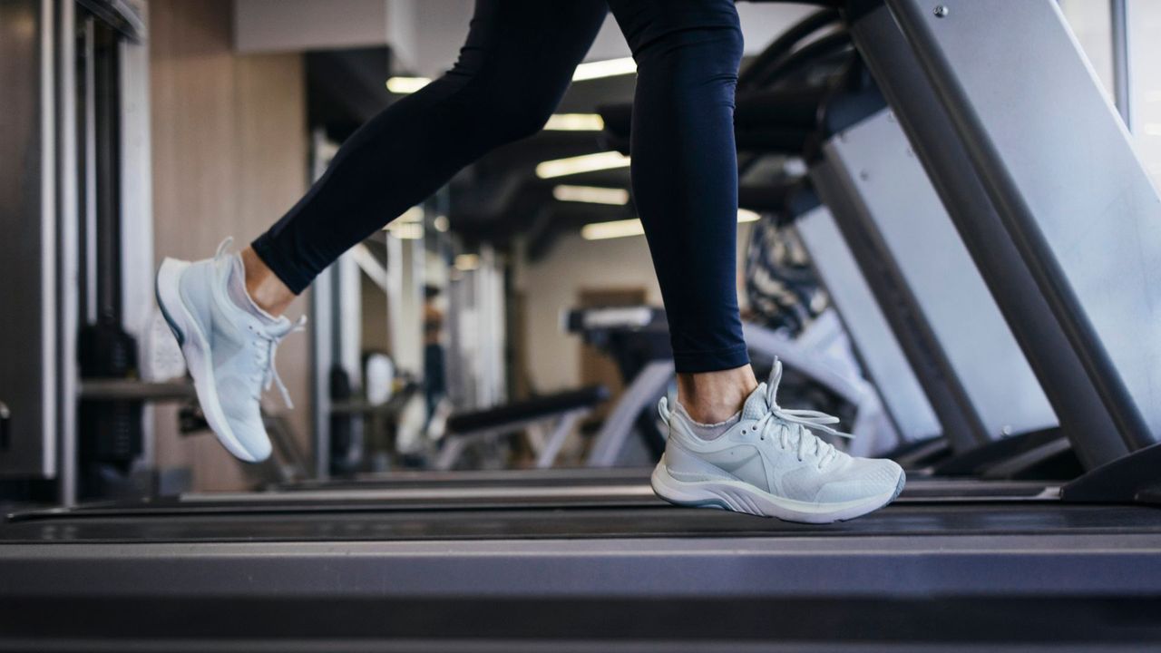 Lower view of woman&#039;s legs on treadmill at the gym doing treadmill workouts