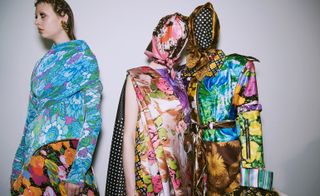 Models wear a range of floral print tops and dresses, some covering heads and faces as a mask