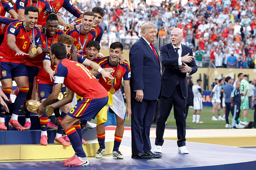 Rodri #16 of Spain lifts the trophy while US President Donald Trump and FIFA President Gianni Infantino look on during the trophy ceremony following the FIFA World Cup 2026 Final