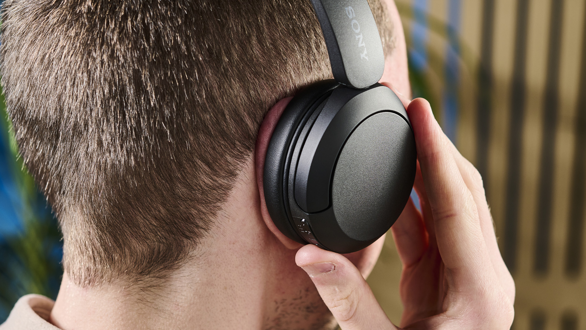 A photo of the Sony WH-CH520 over ear headphones in use with one of the buttons being pressed