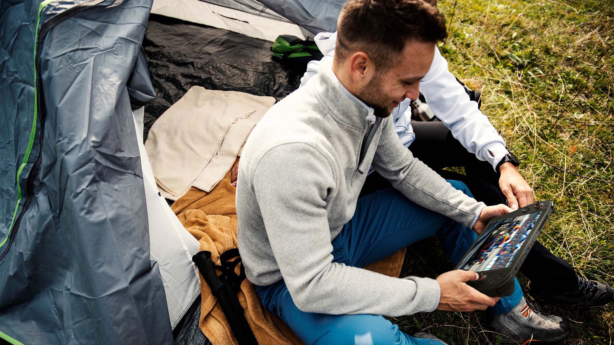 A man sitting in a tent playing the Acer Nitro Blaze 11.