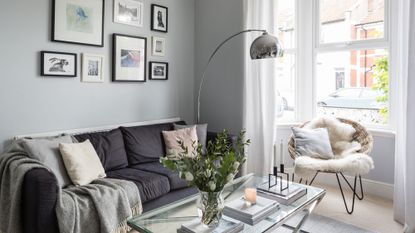 grey living room with grey sofa and chrome arched overhead lamp and glass table