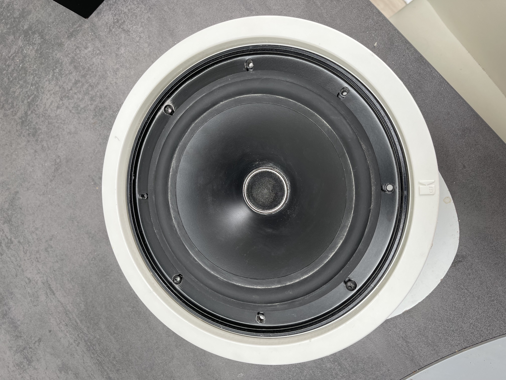 A close up of a KEF in-ceiling speaker
