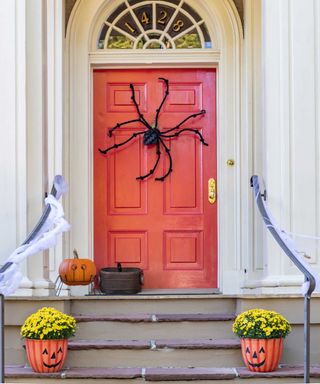 front door with giant spider decoration and pumpkin flowerpots