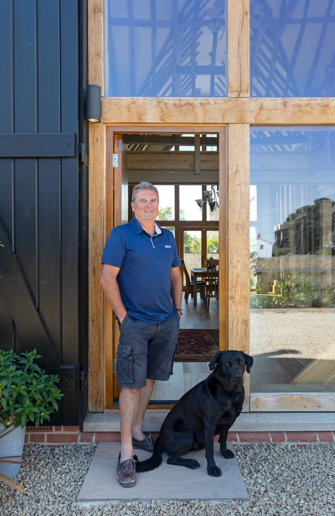 A homeowner stands outside his barn conversion with a black Labrador dog
