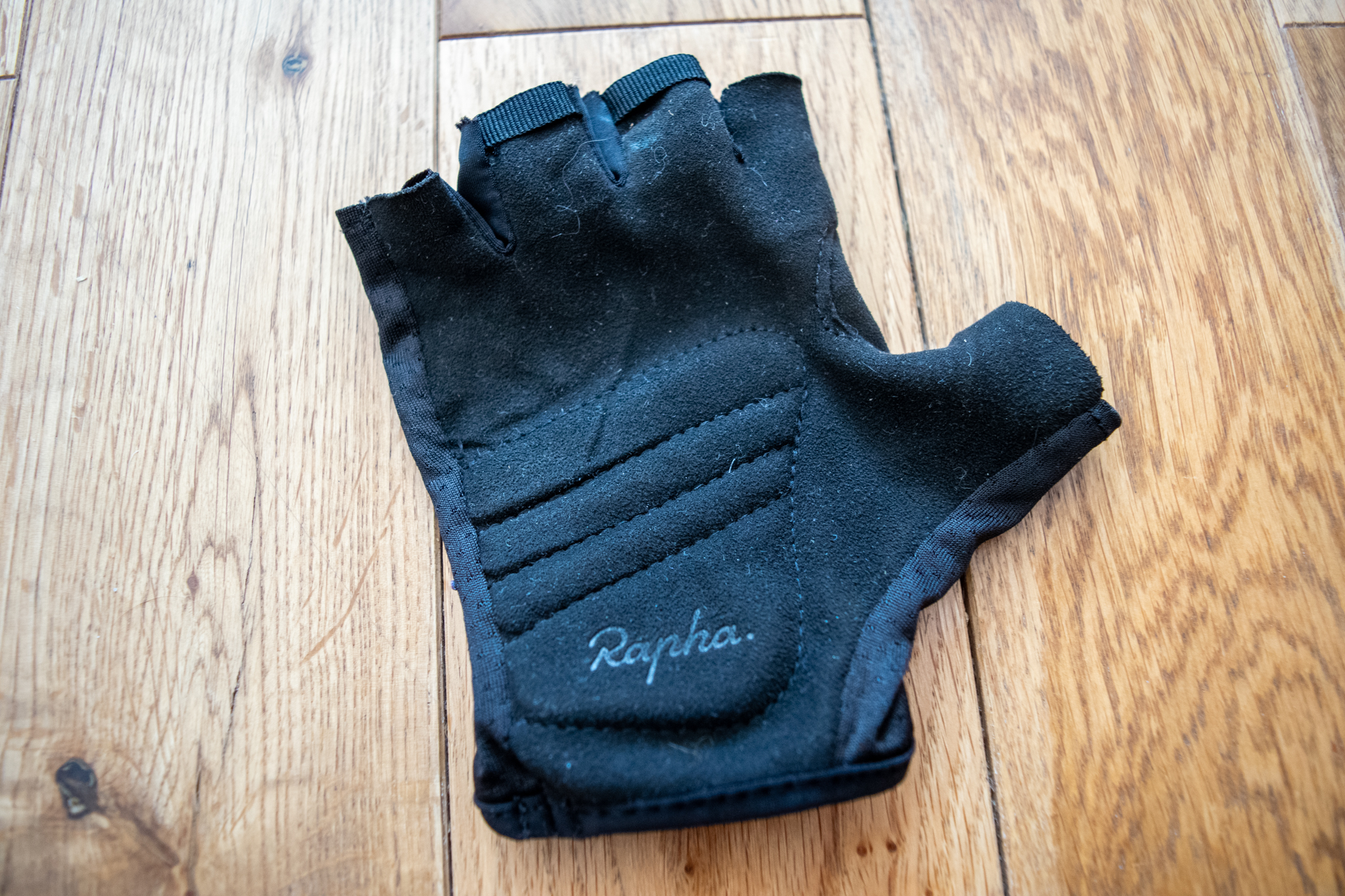 A black Rapha Core cycling mitt on a wooden floor