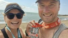 Woman and man stand with medals around their necks and the sea in the background