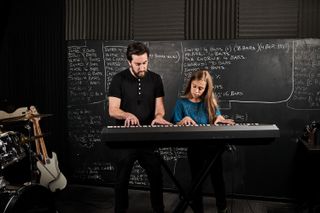 A man teaches a young girl piano