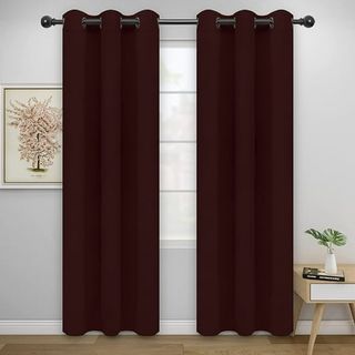 A pair of dark red thermal curtains hanging either side of a window on a grey wall. 