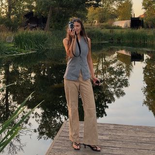 A woman wears corduroy pants, black heels, and a denim vest.