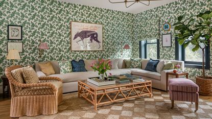 a green floral wallpapered family room with a large sectional couch, diamond woven rattan rug, wicker furniture and eclectic artwork