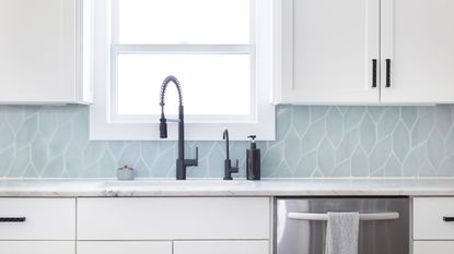 Blue modern edged tiled backsplash in modern kitchen with white gloss finished cabinets