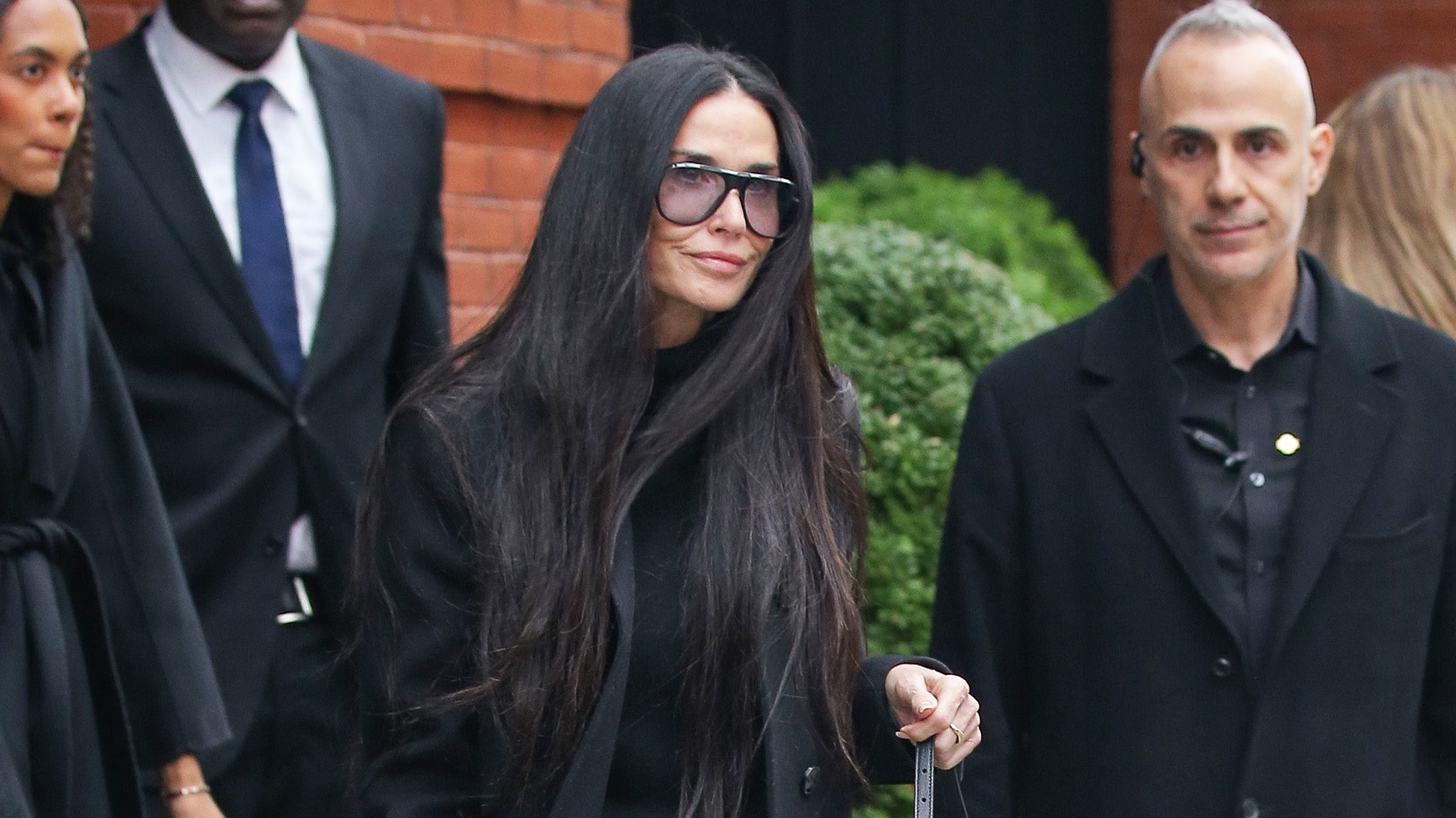 Demi Moore wearing a black coat, sweater, and jeans with Gucci shoes and the Gucci Jackie Slim Shoulder Bag