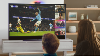 Boy and girl watching football on Sky Glass TV with Watch Together Sky Live feature on right hand side of the screen