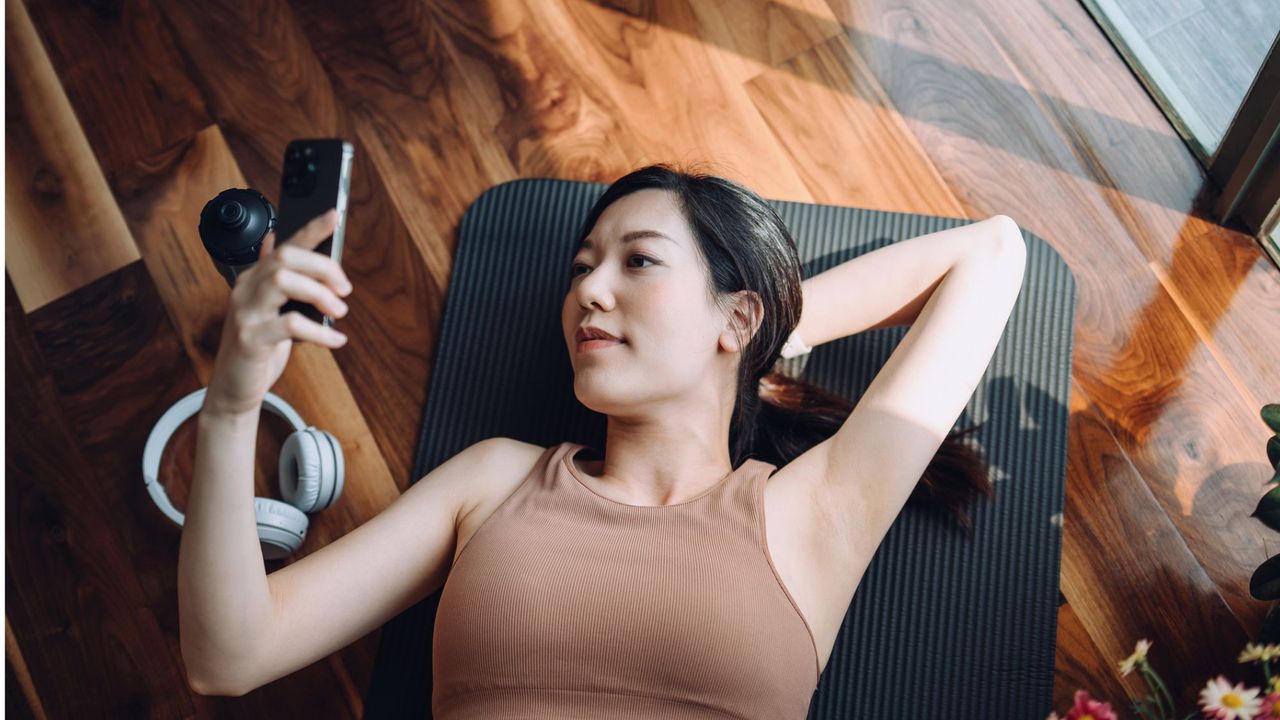 A woman lying on the floor after using one of the best fitness apps