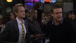 Barney and Marshall sitting together at the bar in How I Met Your Mother.