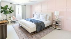 Modern bedroom with light pink wall paneling, white bed sheets, and denim throw