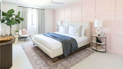 Modern bedroom with light pink wall paneling, white bed sheets, and denim throw
