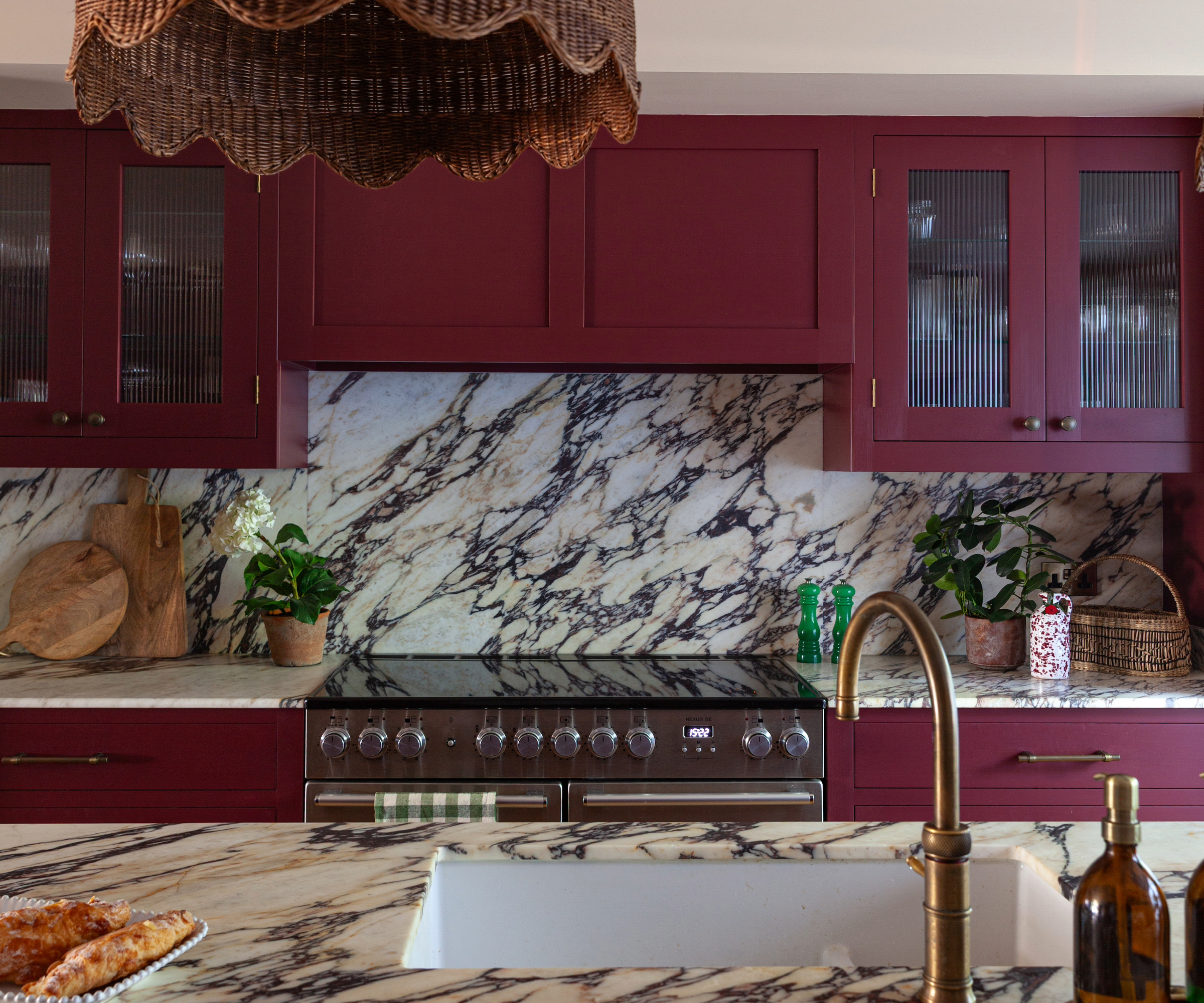 Kitchen with marble kitchen worktops and splashback and red cabinets