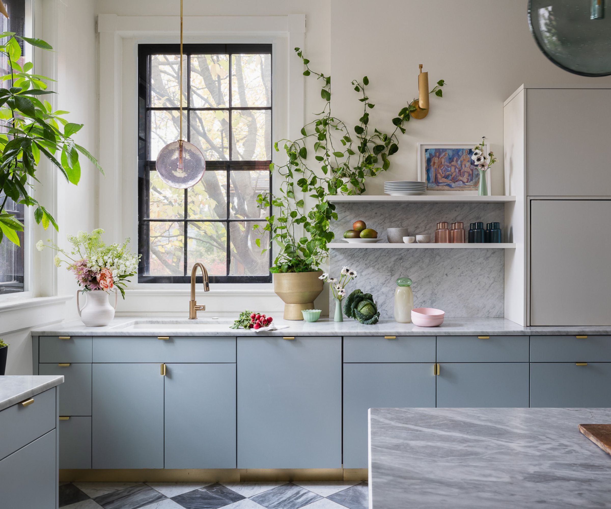 A blue and white kitchen with marble countertops and large black sash windows