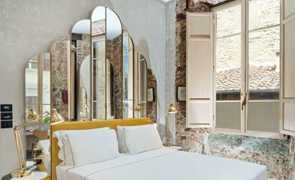 Bedroom featuring mirrored headboard and exposed brickwork