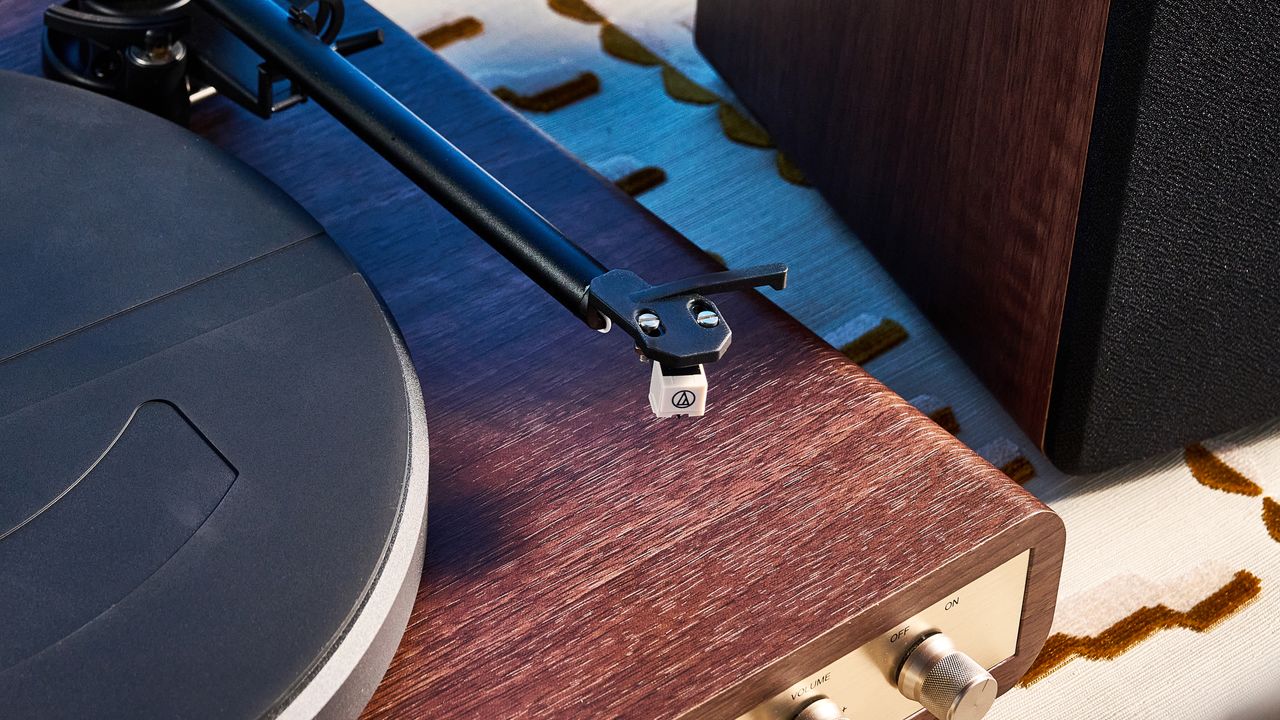 Crosley C65 turntable and bookshelf speakers photographed in front of a blue background on a brown table.