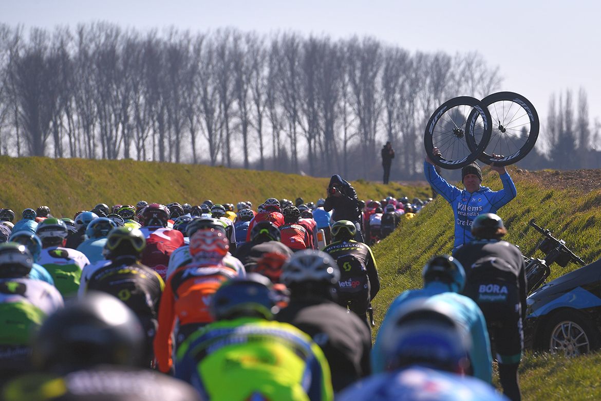 Team staff wait with wheels on the cobbles