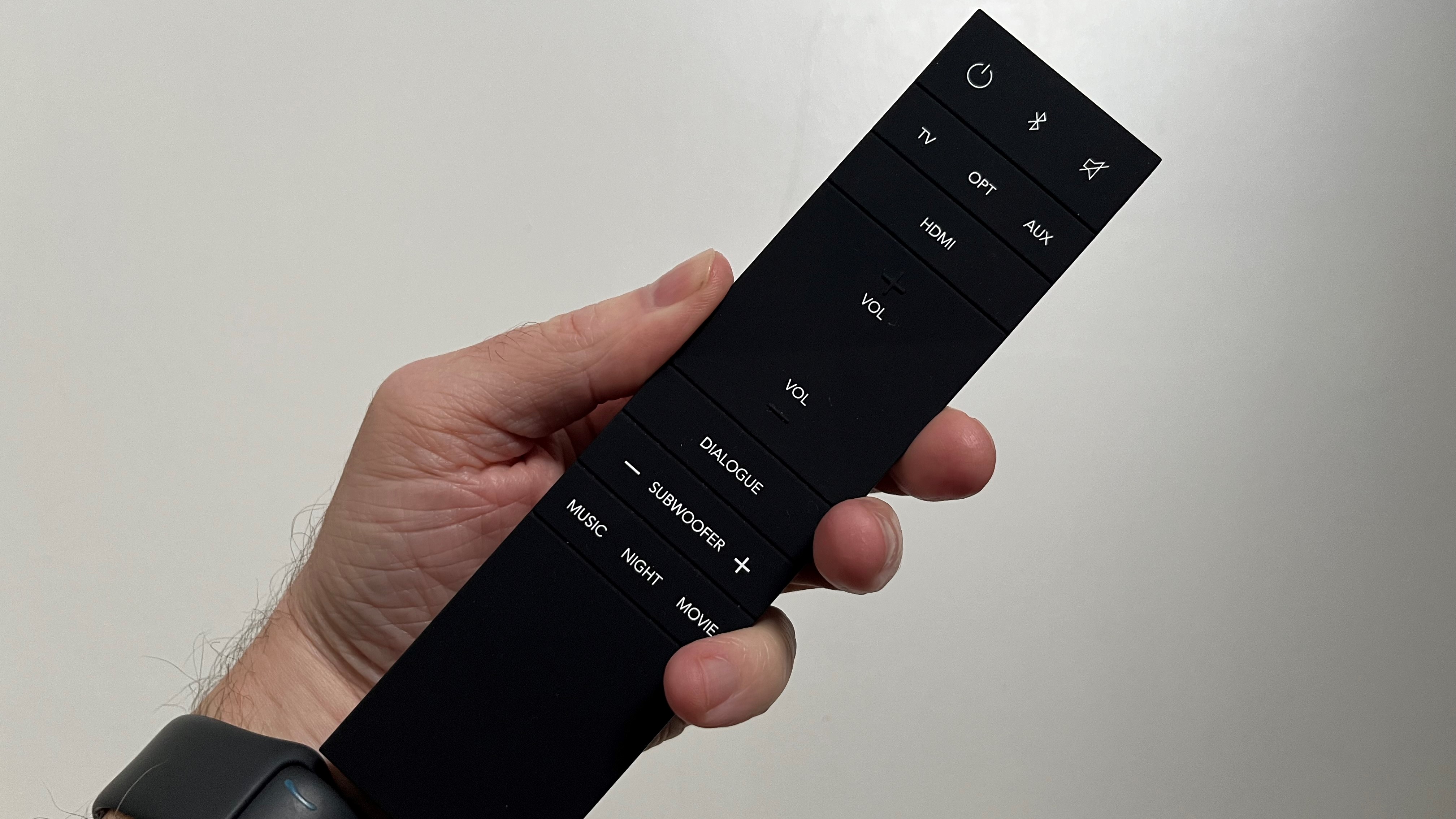 Definitive Technology Studio 3D Mini soundbar remote control held in hand against white background