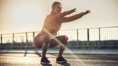 A woman performing a squat outside 