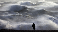 A person stands on the shoreline in Newhaven watching huge weaves during Storm Henk