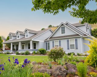 Suburban home exterior at sunset with landscaped lawn and garden visible