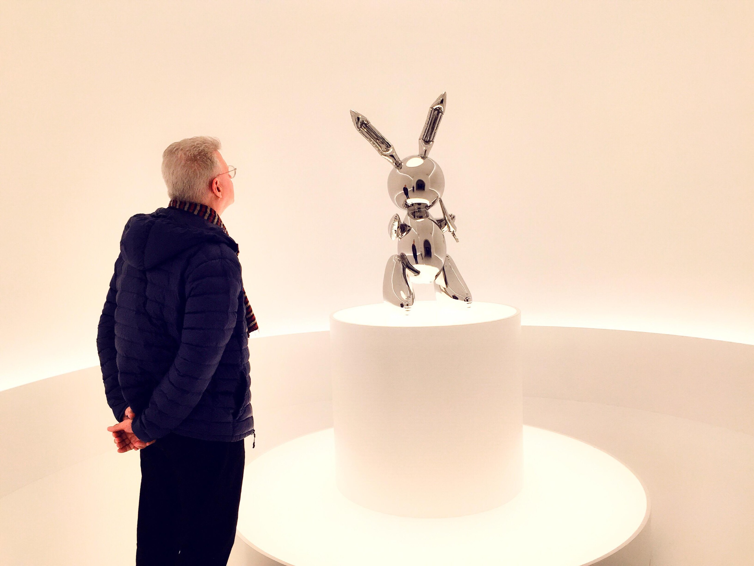 A man looks at Jeff Koons's stainless steel sculpture Rabbit.