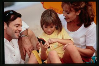 Promotional material of a man and woman holding a girl using a phone, 1990s