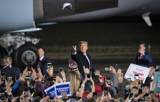 U.S. President Donald Trump tosses a cap at attendees as he arrives at a rally in Duluth, Minnesota, on Wednesday, Sept. 30, 2020.